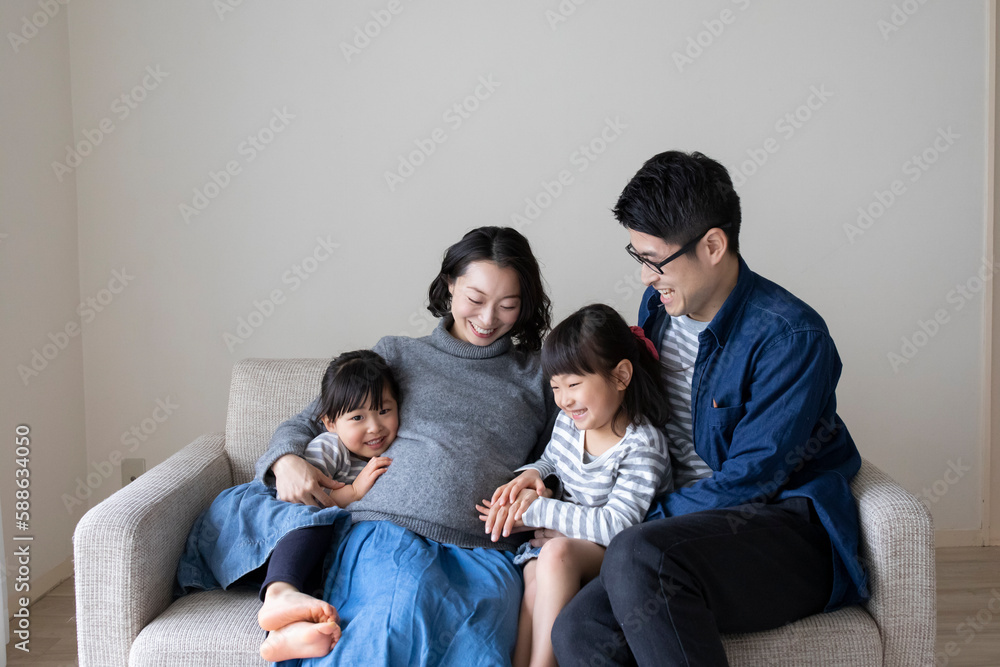 妊婦の母親のお腹に寄り添う姉妹と父親