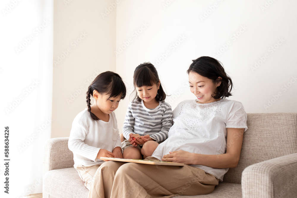 ソファーでくつろぐ母親と幼い姉妹 ソファーでくつろぐ母親と幼い姉妹