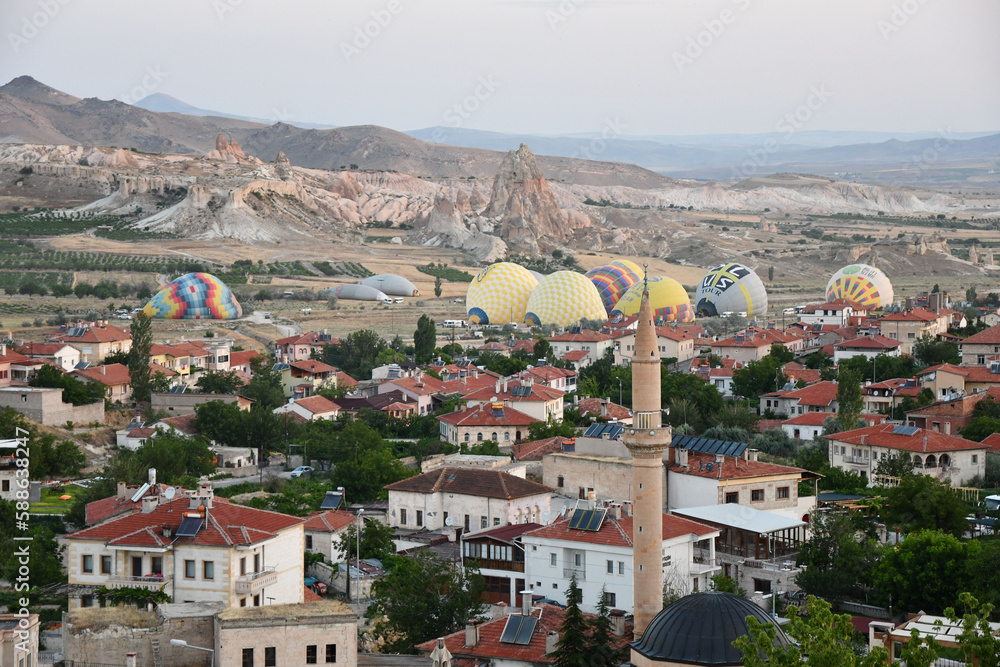Aerial view of the village of Cavusin, the minaret and hot air balloons in the background in Turkey