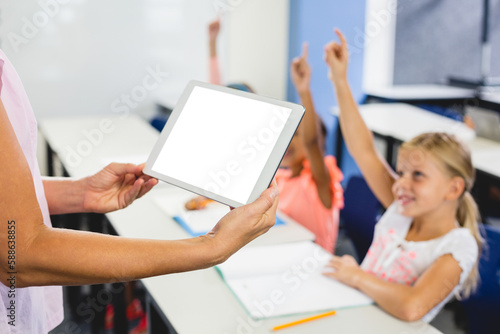 Female teacher holding digital tablet in classroom