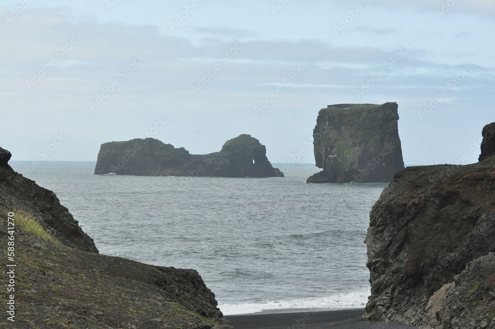 Scenic view of Icelandic coastline with waves hitting huge black rocks at overcast Dyrholaey Cape