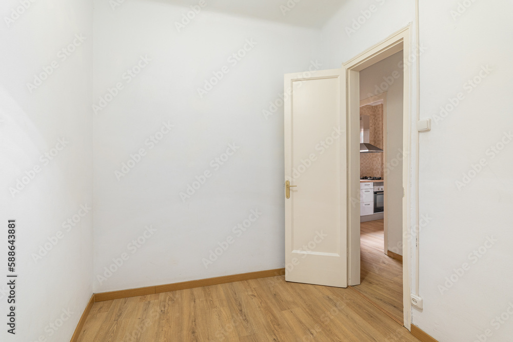 Empty white room with a front door and a view of a cozy kitchen with wooden laminate in a new apartment. Concept of preparation for furnishing and housewarming. Copyspace Empty white room with a front door and a view of a cozy kitchen with wooden laminate in a new apartment. Concept of preparation for furnishing and housewarming. Copyspace