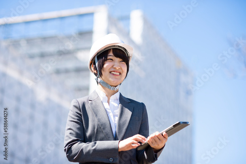 工事現場でタブレットPCを持ち微笑むビジネスウーマン photo
