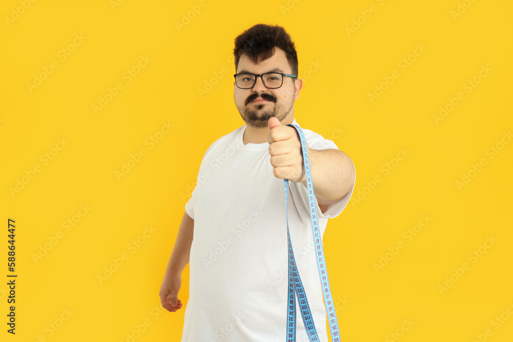 Concept of weight loss, young man on yellow background Concept of weight loss, young man on yellow background
