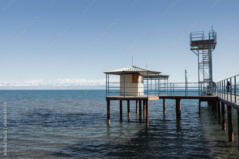 Sunny Pier on Lake with Snowy Mountains in the Distance