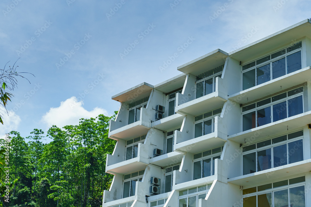 Hotel building with balconies against the blue sky and trees Hotel building with balconies against the blue sky and trees