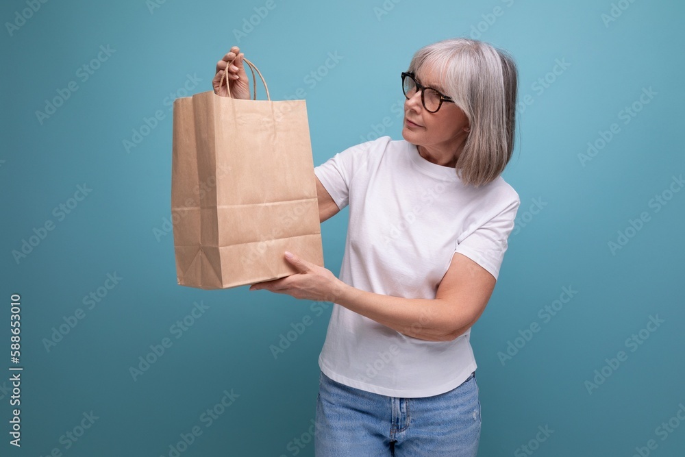 60s woman with gray hair holding kraft eco friendly bag on studio background 60s woman with gray hair holding kraft eco friendly bag on studio background