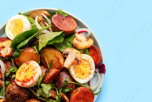 Plate of tasty potato salad with eggs and mushrooms on light blue background  top view