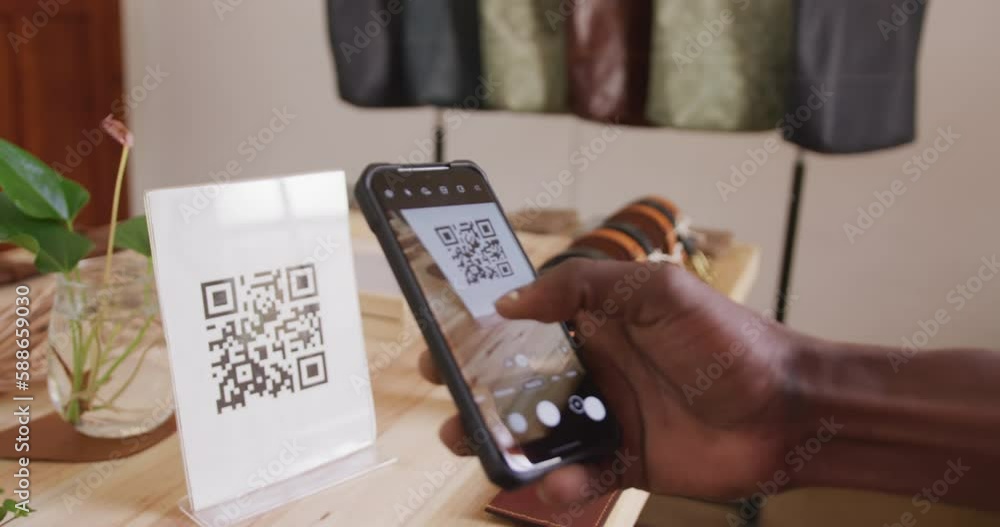 Hand of african american craftsman scanning qr code in leather workshop