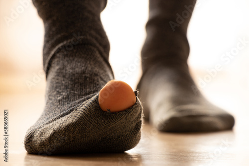 Women's feet in holey socks stand on the floor of the house, poverty, feet in socks