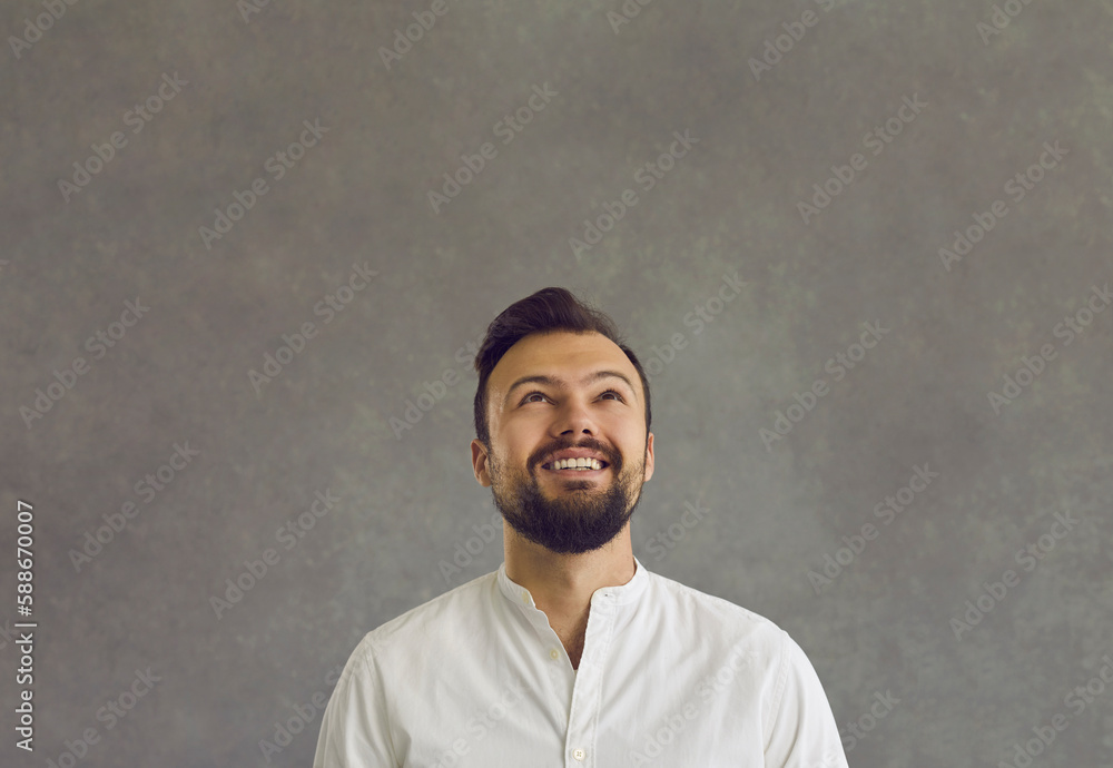 Headshot portrait of happy smiling caucasian man looking up standing over studio wall. Millennial guy waiting for miracle, dreaming about future. Advertisement, idea, inspiration and people concept Headshot portrait of happy smiling caucasian man looking up standing over studio wall. Millennial guy waiting for miracle, dreaming about future. Advertisement, idea, inspiration and people concept