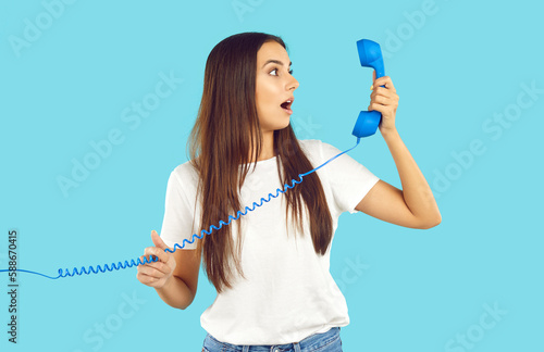 Εκτύπωση καμβά Shocked young woman looking at retro phone receiver in surprise