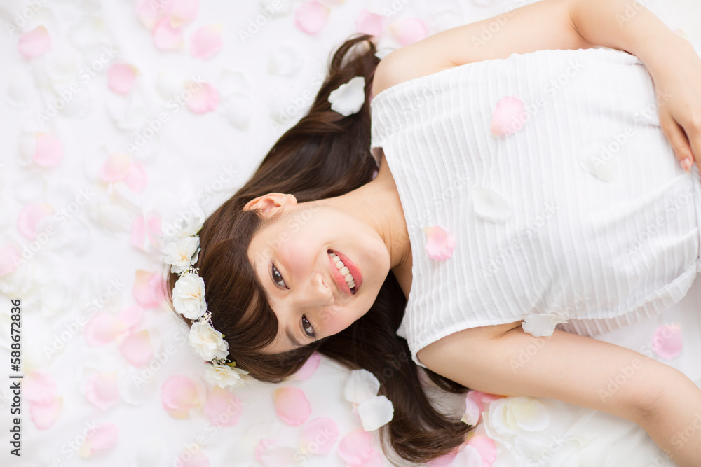Naklejka premium 床にまかれた花びらの上に寝転ぶ女性