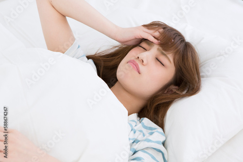 ベッドで頭痛に悩む女性