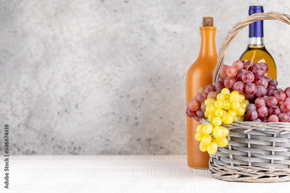 Obraz premium Ripe grape in basket and wine bottles