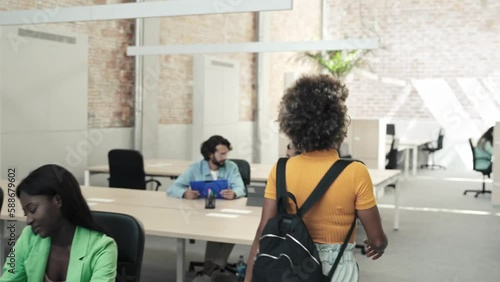 Young African American professional woman walking arriving to the office and joining business colleagues to start working