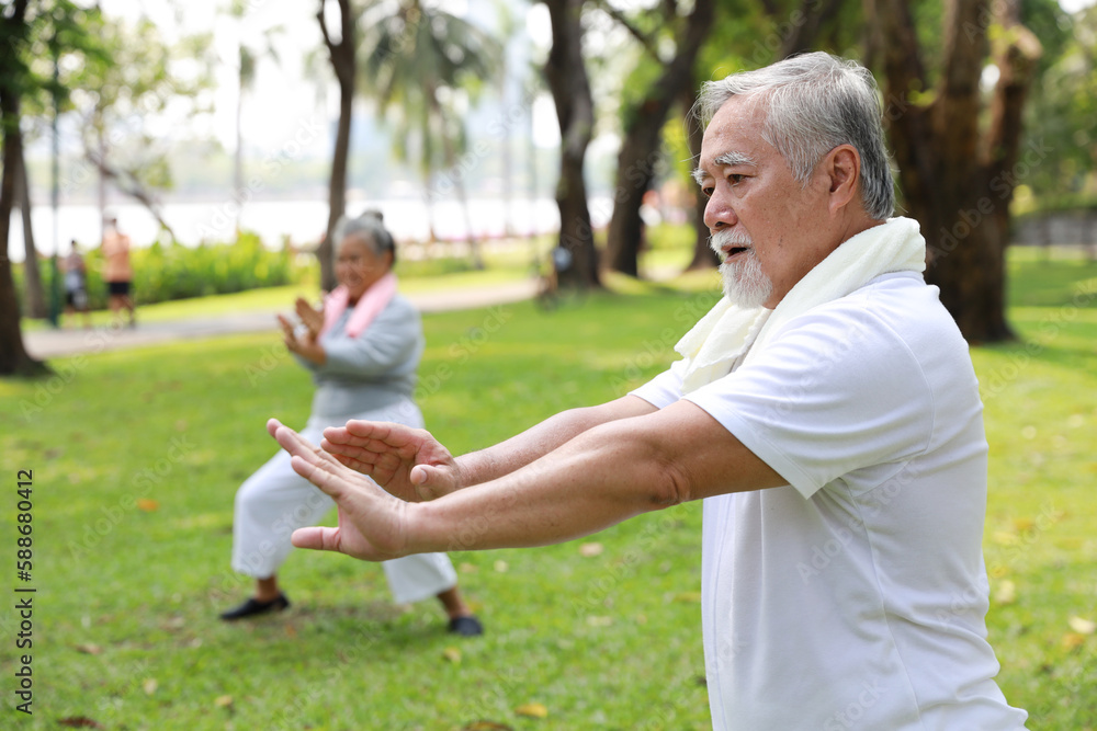 Fototapeta premium Asian senior couple practice yoga excercise, tai chi tranining, stretching and meditation together with relaxation for healthy in park outdoor after retirement. Happy elderly outdoor lifestyle concept