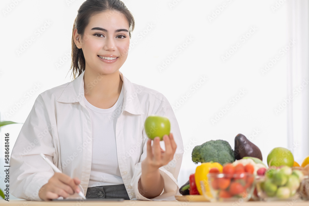 Happy professional nutrition healthful surrounded by a variety of fresh fruits and vegetables working on digital tablet and smiles. concept of right nutrition, diet and healthcare. Happy professional nutrition healthful surrounded by a variety of fresh fruits and vegetables working on digital tablet and smiles. concept of right nutrition, diet and healthcare.