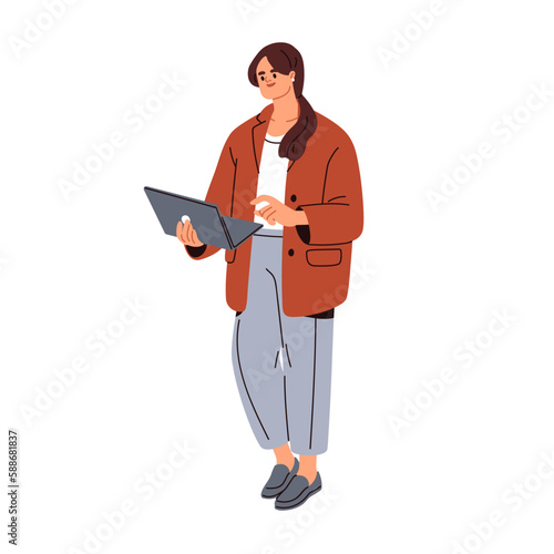 Business woman works at laptop. Young businesswoman standing, holding noteboo...