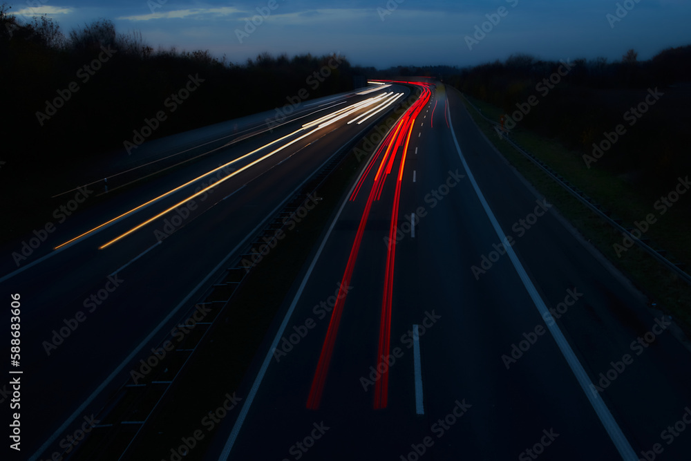 Light Trails on a Dark Highway.The night sky is illuminated by long exposure trails of speeding tail lights, emphasizing the infrastructure and motion of a dark highway in this photo.