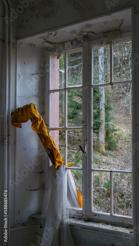 Fenêtre cassée avec un rideau à travers dans une maison abandonnée