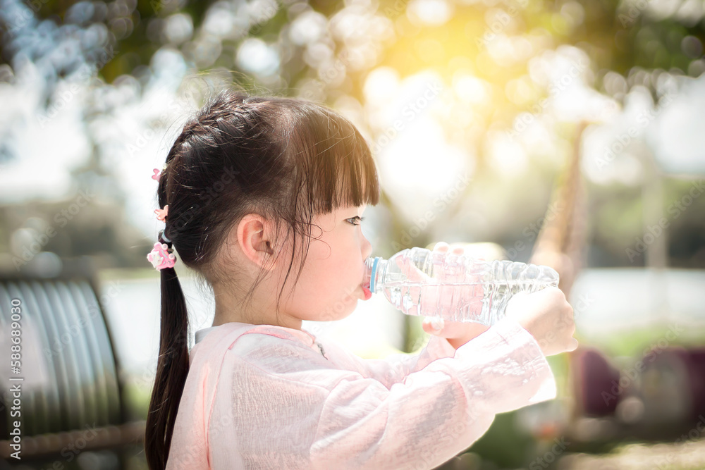 Obraz premium A little Asian girl is drinking water outdoors