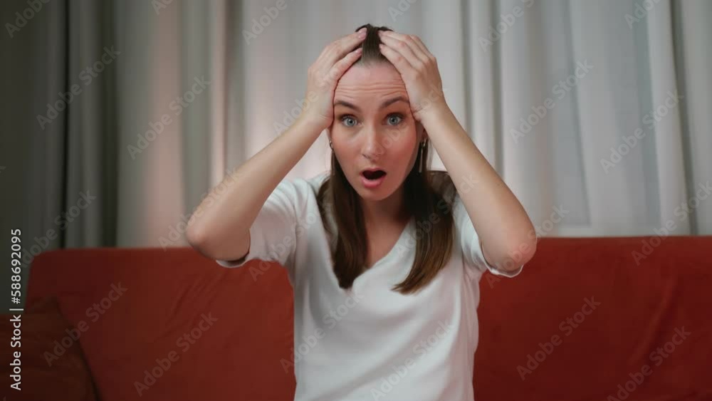 Frightened woman looks into the camera with bulging eyes and wide open mouth, being shocked by what she saw, looks with bated breath. Frightened woman looks into the camera with bulging eyes and wide open mouth, being shocked by what she saw, looks with bated breath.