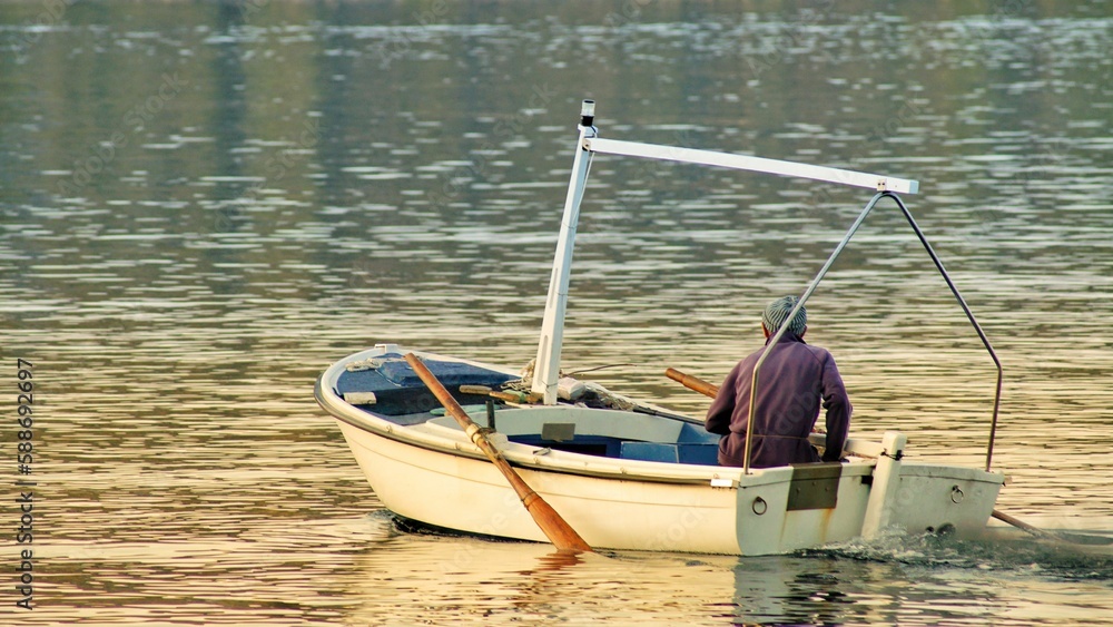 Male fisherman in a small boat peacefully floating down a river