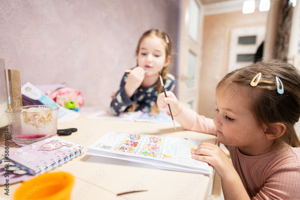 Fototapeta premium Two cute little sisters painting at home.