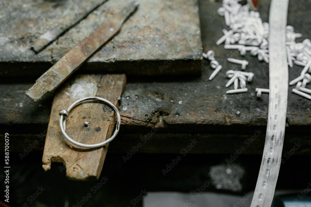 Jeweler at work in jewelry. Desktop for craft jewelry making with professional tools. Close up view of tools. Silver jewelry. Unique local artwork in Nan Province northern thailand Jeweler at work in jewelry. Desktop for craft jewelry making with professional tools. Close up view of tools. Silver jewelry. Unique local artwork in Nan Province northern thailand
