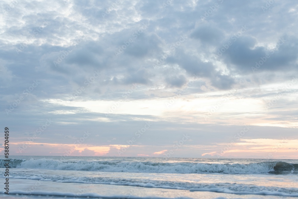 Scenic shot of foamy waves of the sea crashing the shore at sunrise