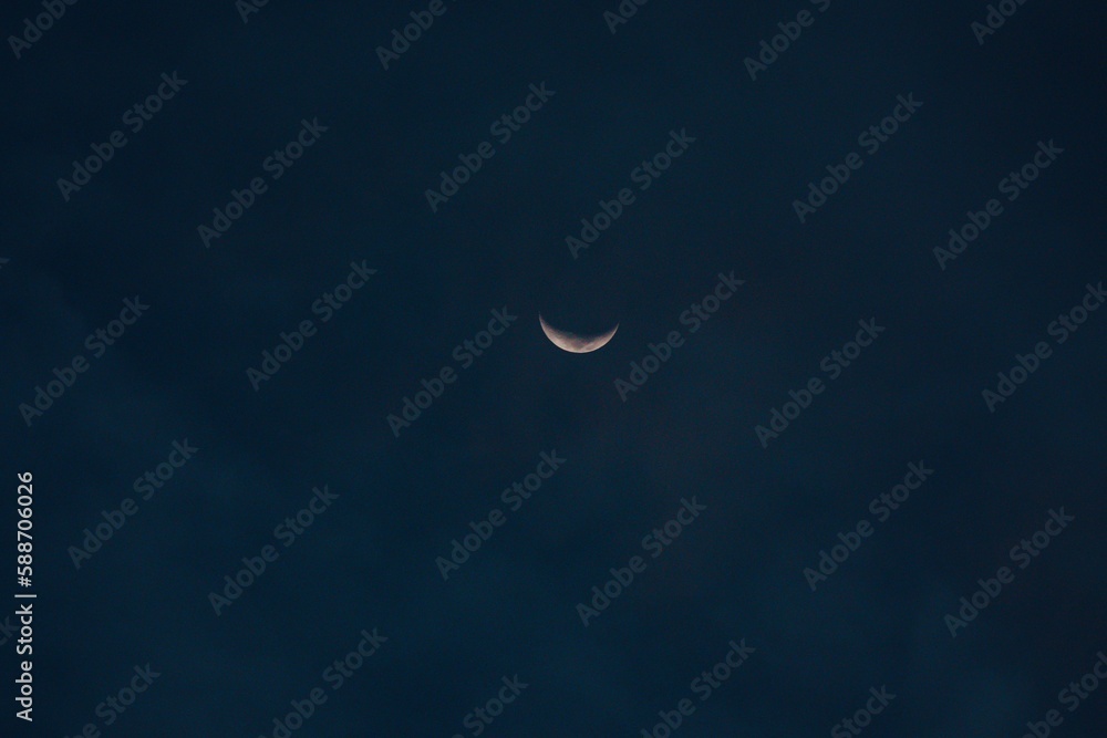 Beautiful crescent moon barely visible in a blue night sky Beautiful crescent moon barely visible in a blue night sky