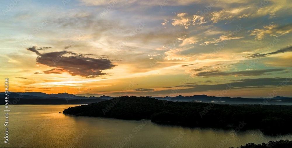 Fototapeta premium Wide angle of Lake Jocassee surrounded by hills and forests at sunrise in South Carolina, USA