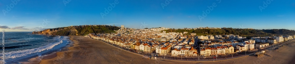 Panoramic shot of the urban houses near the sandy beach against a blue sky