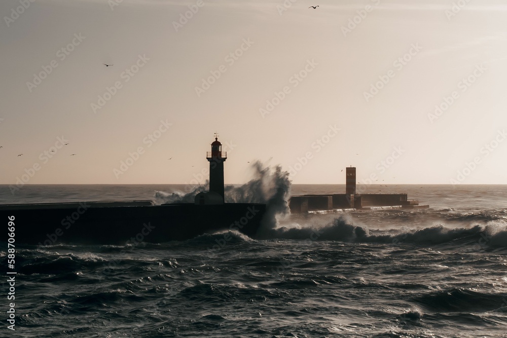 Waves crashing over a lighthouse on a sunny day Waves crashing over a lighthouse on a sunny day