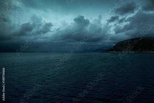 Calm sea with mountains in the background under the stormy dark sky