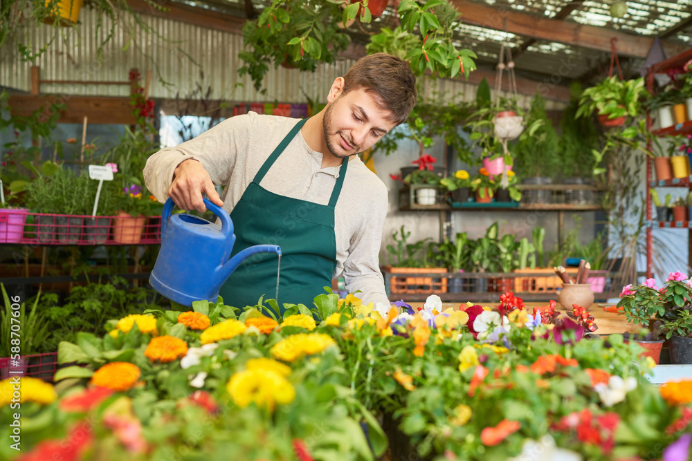 Junger Gärtner mit Gießkanne beim Blumen gießen Junger Gärtner mit Gießkanne beim Blumen gießen
