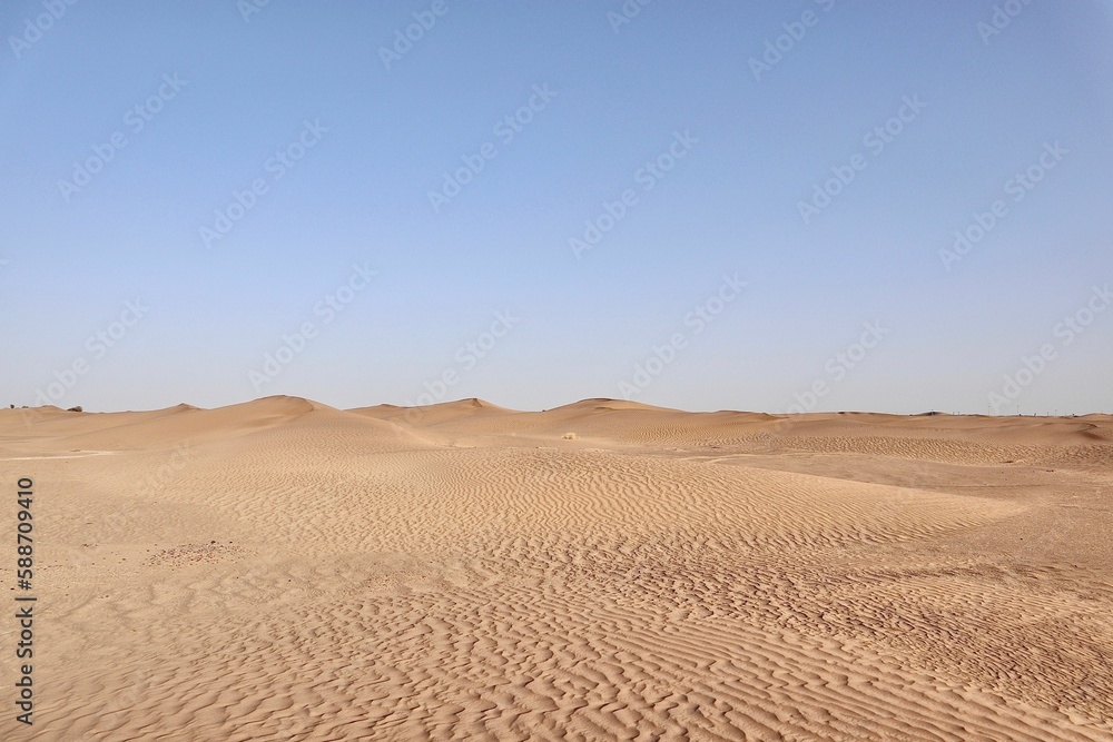 Scenic view of desert against sky under the clear blue sky with the sun shining bright