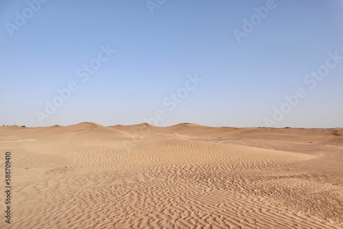Scenic view of desert against sky under the clear blue sky with the sun shining bright