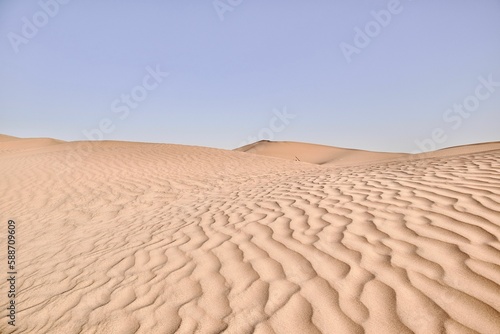 Scenic view of desert against sky under the clear blue sky with the sun shining bright