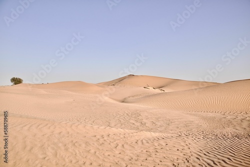 Scenic view of desert against sky under the clear blue sky with the sun shining bright