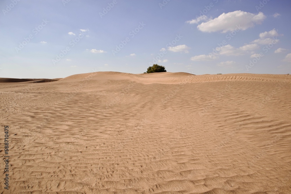 Scenic view of large desert landscape with sand dunes under blue cloudy sky