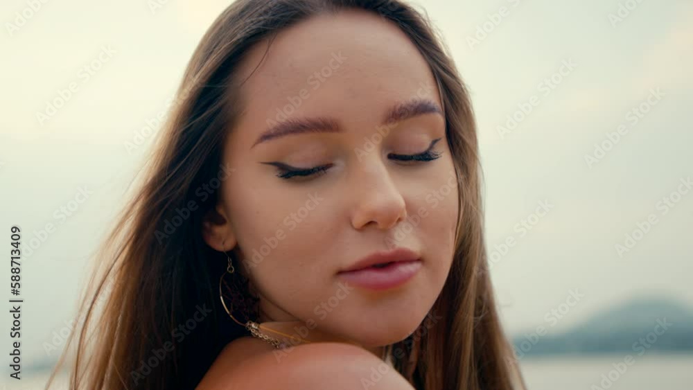 a beautiful girl with long straight hair stands on the beach and looks at camera a beautiful girl with long straight hair stands on the beach and looks at camera