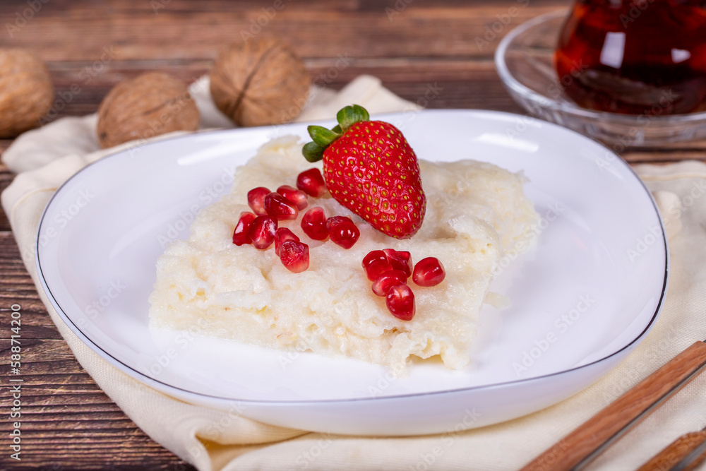Güllaç dessert with pomegranate and strawberry. Ramadan dessert. Gullac dessert with walnuts on wooden background. Close up Güllaç dessert with pomegranate and strawberry. Ramadan dessert. Gullac dessert with walnuts on wooden background. Close up