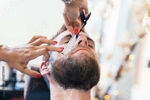 Worker shaving a client in a hairdresser