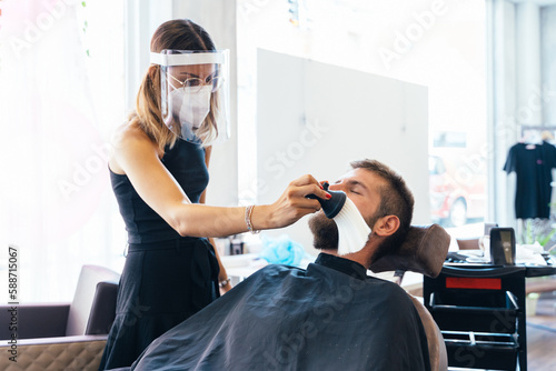 Hairdresser removes cut hairs from a client's face