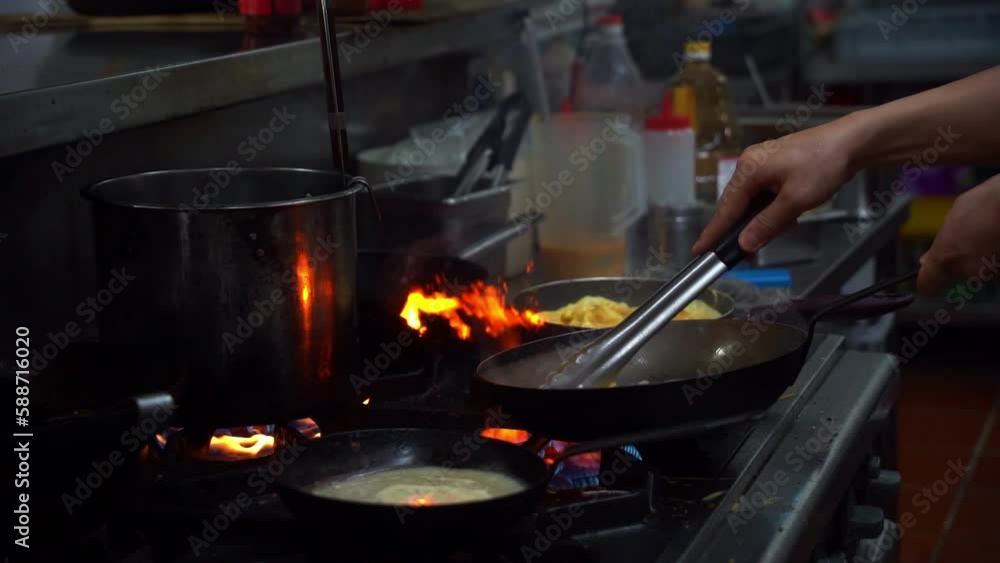Slow motion close up shot capturing a professional chef swirling the frying pan with corns and hams, mixing the ingredients on stovetop cooking in commercial kitchen. Slow motion close up shot capturing a professional chef swirling the frying pan with corns and hams, mixing the ingredients on stovetop cooking in commercial kitchen.