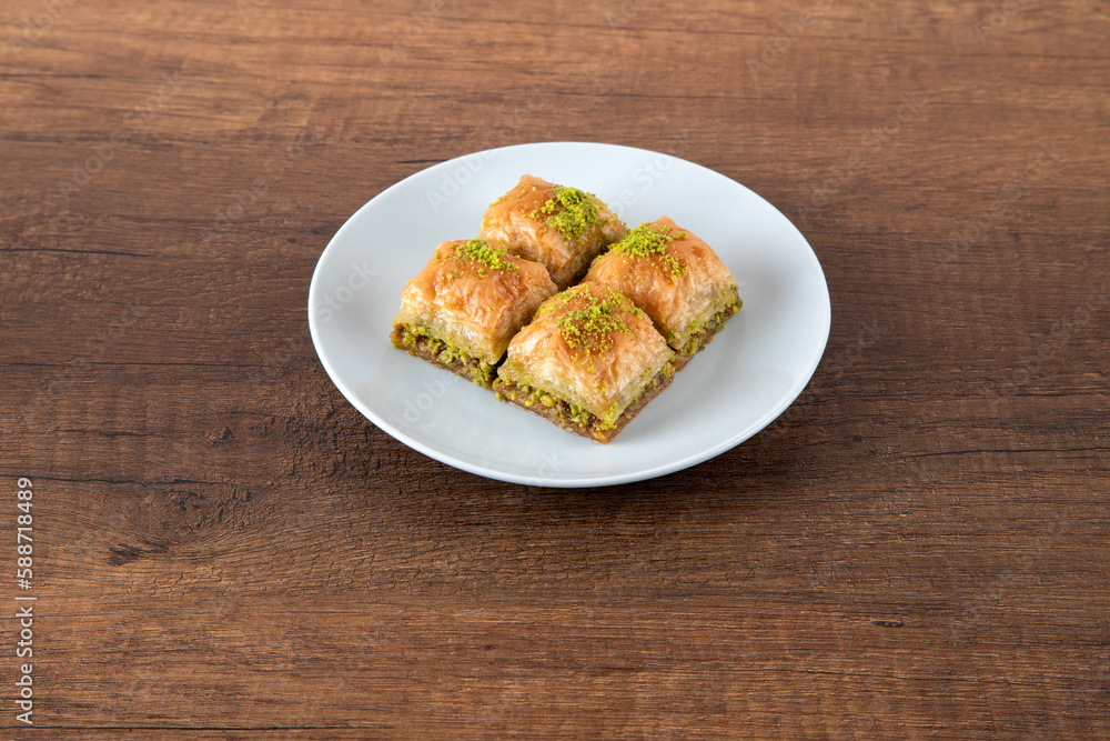Turkish baklava with pistachio in plate.A plate baklava on wooden background,top view
Turkish baklava with pistachio in plate.A plate baklava on wooden background,top view