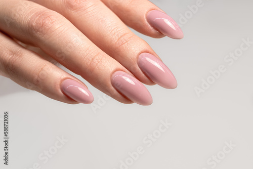 Beautiful manicure with pink nude gel polish. Manicure for women with gel polish. Long nails in the form of almonds. Perfect nude manicure