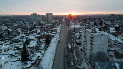 Aerial view of evening traffic in a snowy city at sunset. Winter cityscape.